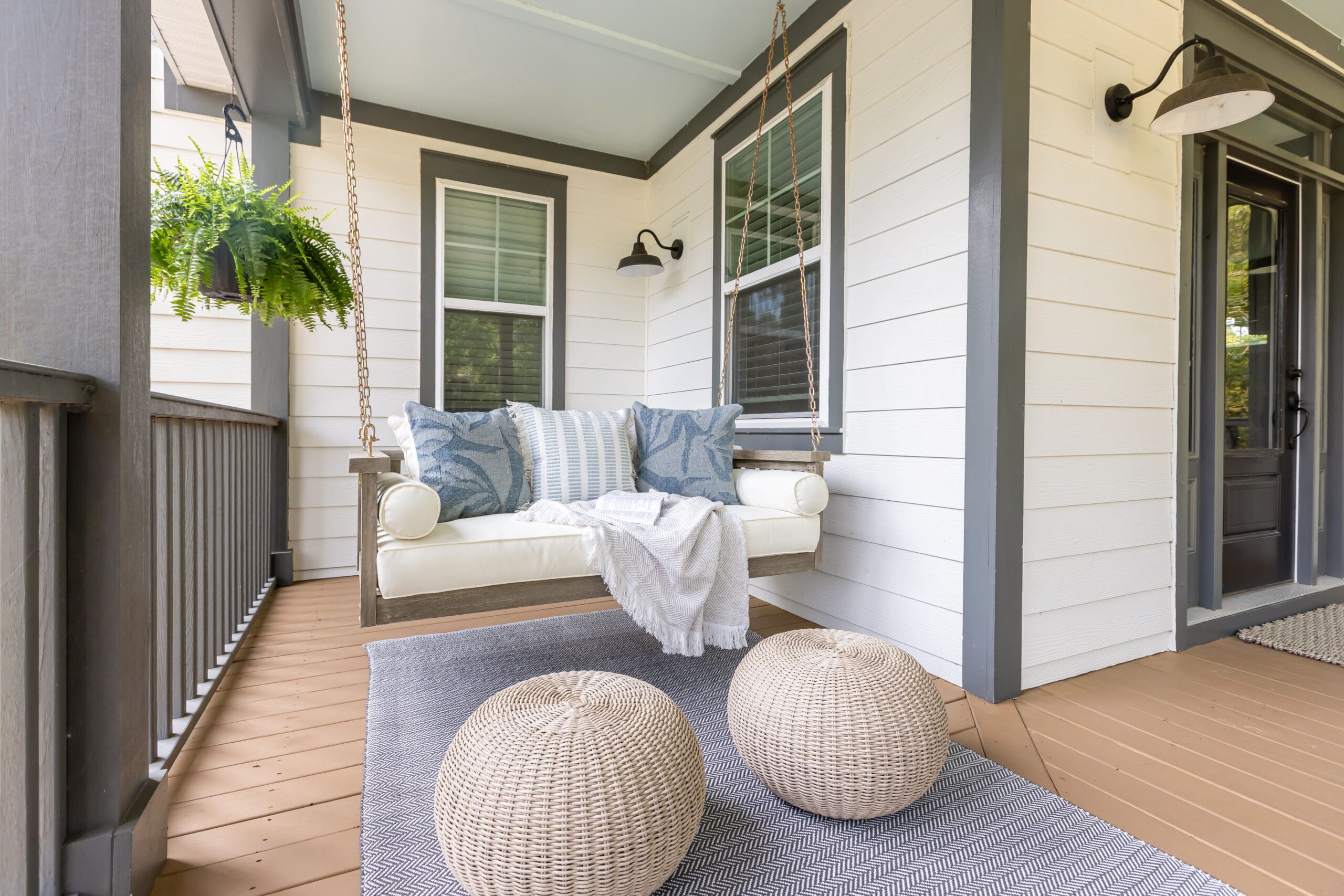 Southern porch swing styled for comfort with pillows and greenery